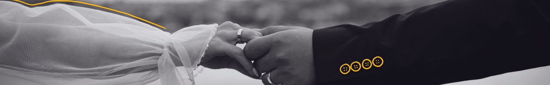 Gros plan en noir et blanc sur les alliances et les mains enlacées pour un mariage sur mesure.